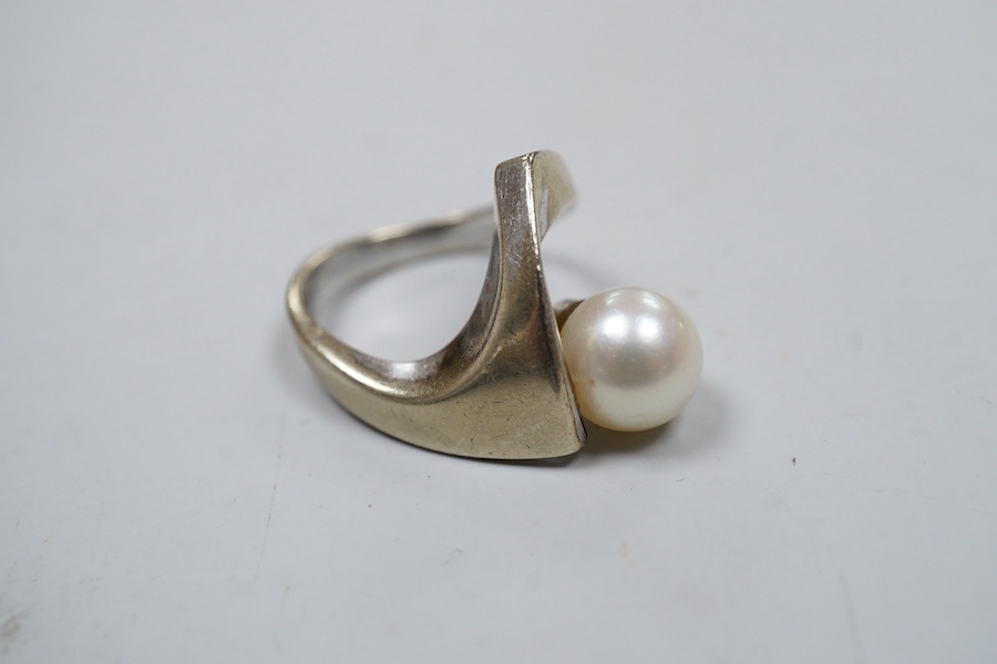 A cultured pearl ring, set with a cultured pearl, to an asymmetrical curved mount in white gold, size J1/2, stamped K14WG, maker's mark, gross weight 6 grams, Condition: Overall good - wear to rhodium, glue residue to ba